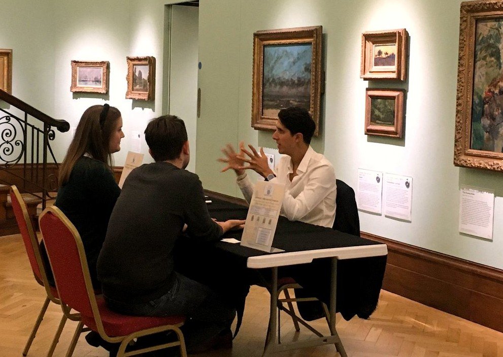 Lawrence Rook giving a hand reading to a couple in an art gallery